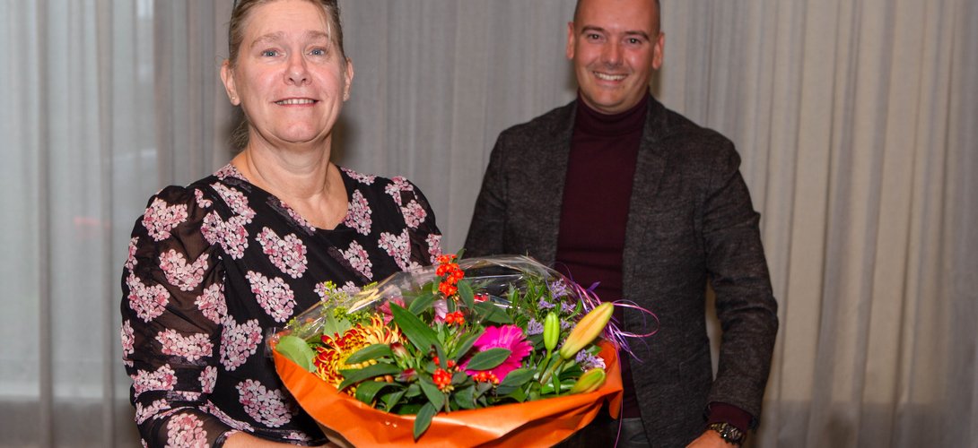 Irona Groeneveld ontvangt uit handen van Jaap van Veen (DB-lid met portefeuille financiën) een bos bloemen. 