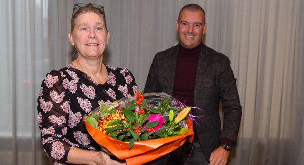 Irona Groeneveld ontvangt uit handen van Jaap van Veen (DB-lid met portefeuille financiën) een bos bloemen. 
