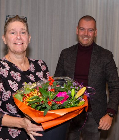Irona Groeneveld ontvangt uit handen van Jaap van Veen (DB-lid met portefeuille financiën) een bos bloemen. 
