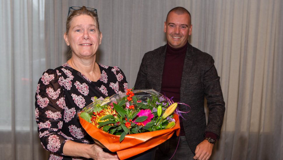 Irona Groeneveld ontvangt uit handen van Jaap van Veen (DB-lid met portefeuille financiën) een bos bloemen. 