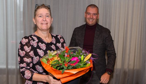 Irona Groeneveld ontvangt uit handen van Jaap van Veen (DB-lid met portefeuille financiën) een bos bloemen. 