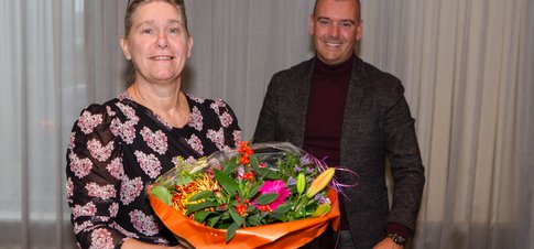 Irona Groeneveld ontvangt uit handen van Jaap van Veen (DB-lid met portefeuille financiën) een bos bloemen. 