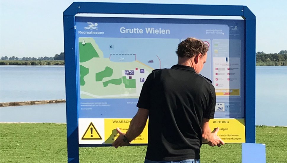 Izaak hangt waarschuwingsbord op bij officiële zwemwaterlocatie