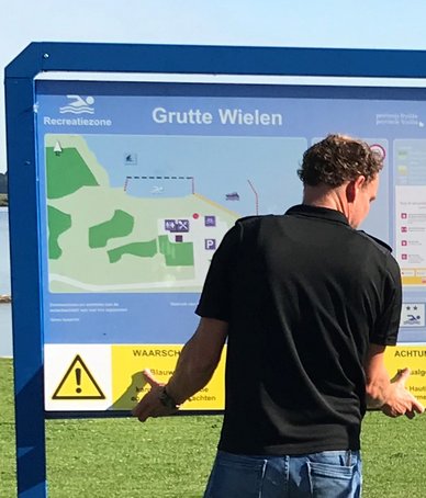 Izaak hangt waarschuwingsbord op bij officiële zwemwaterlocatie